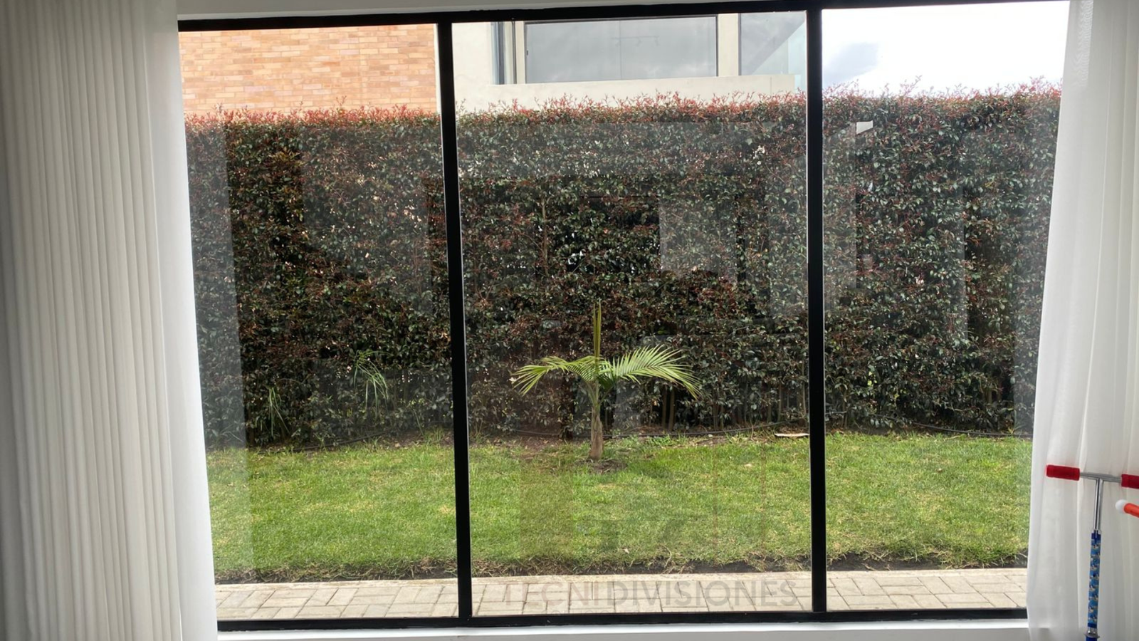 Ventana corrediza en aluminio de gran formato con vidrio instalada en sala con vista al jardín en Bogotá.