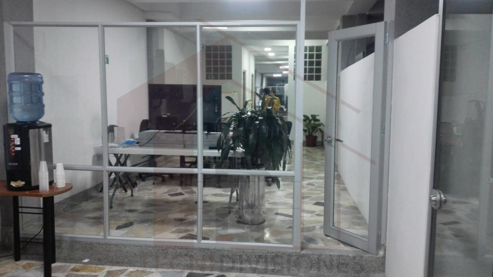 División de oficina en aluminio con vidrio y puerta abatible instalada en Bogotá.