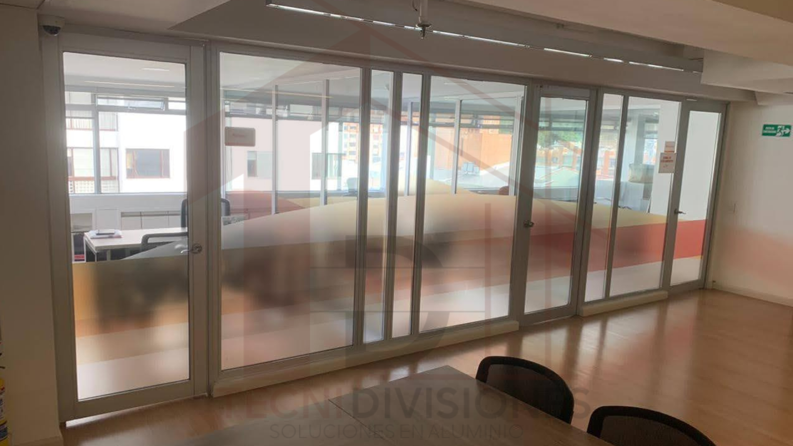División corrediza en aluminio y vidrio con diseño esmerilado para oficinas modernas.