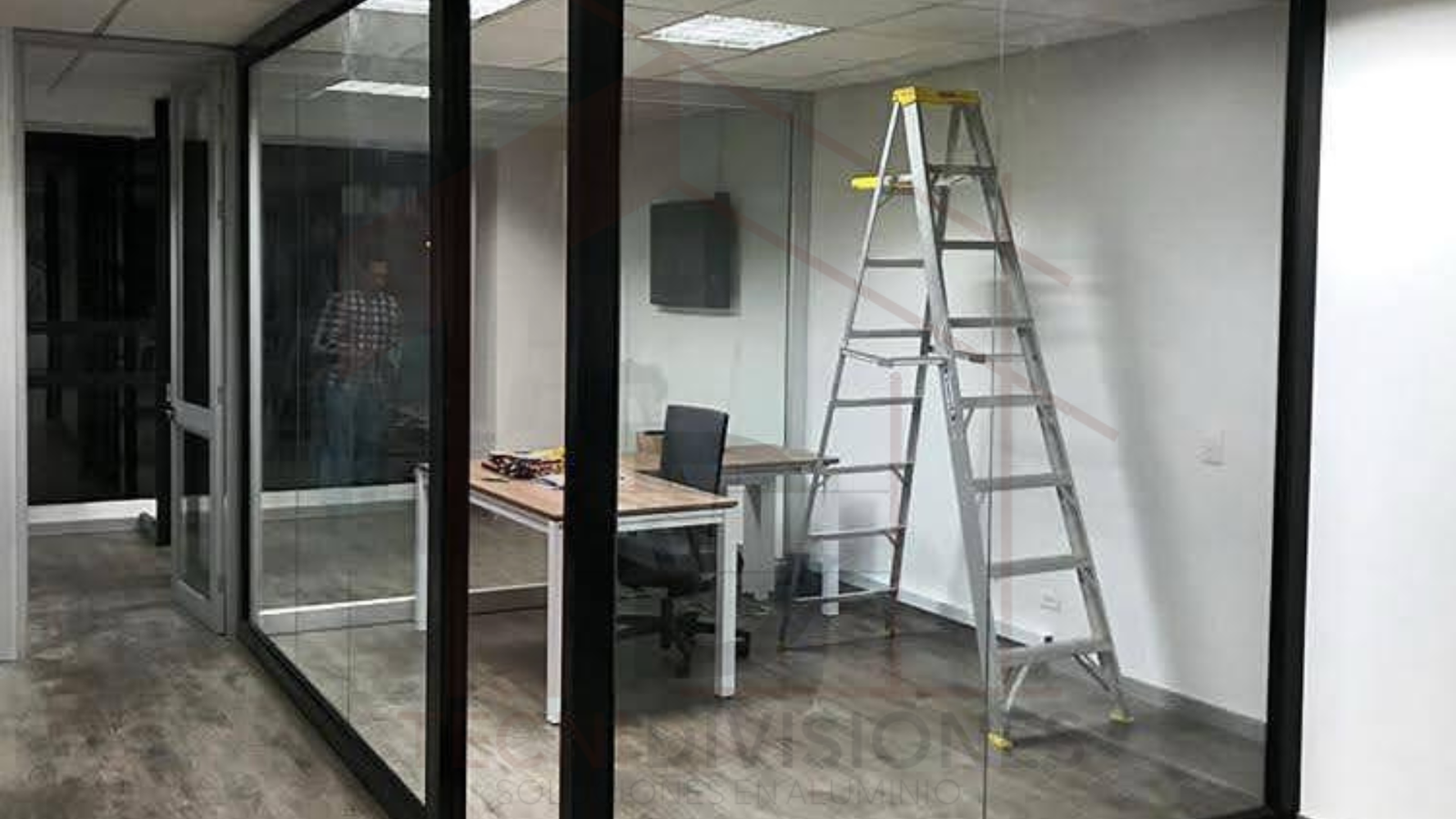División de oficina en vidrio templado con perfilería en aluminio negro instalada en Bogotá.