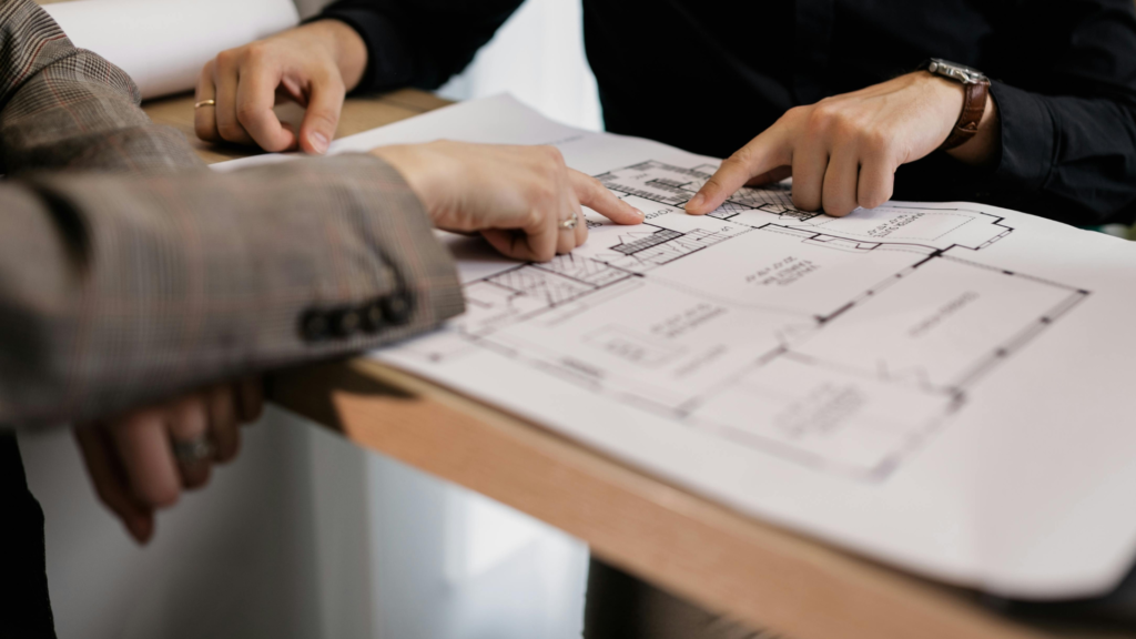 Asesores revisando planos arquitectónicos para diseño de divisiones en aluminio y mobiliario a medida en Colombia