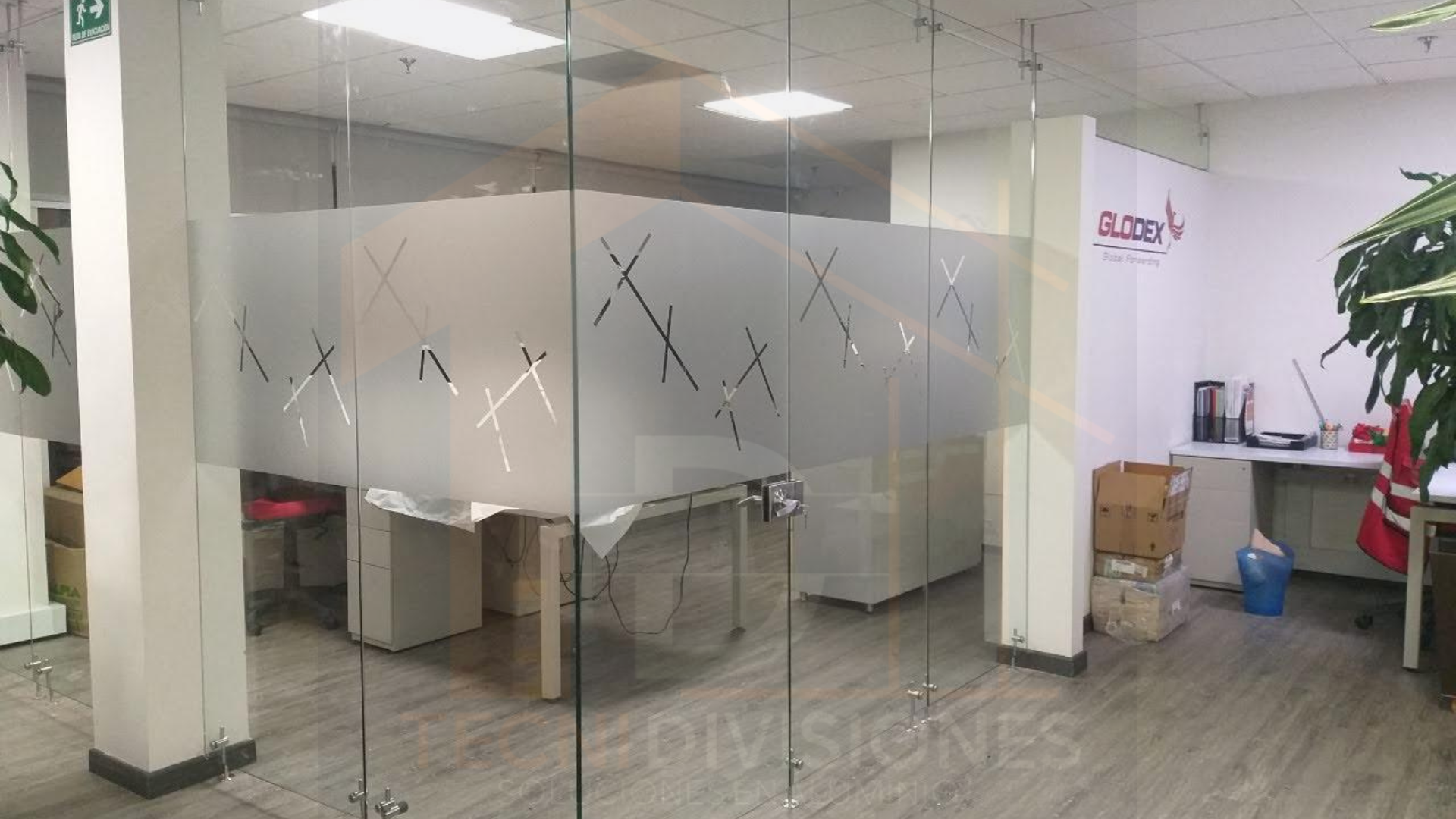 División en vidrio templado con vinilo esmerilado decorativo y herrajes en acero inoxidable para oficina